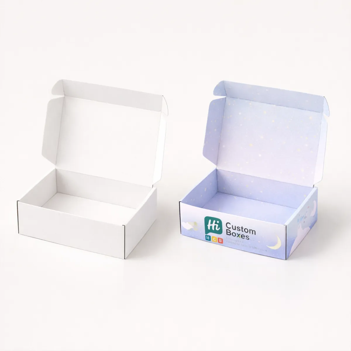 An open plain white mailer box beside a lilac box featuring a crescent moon design- class=